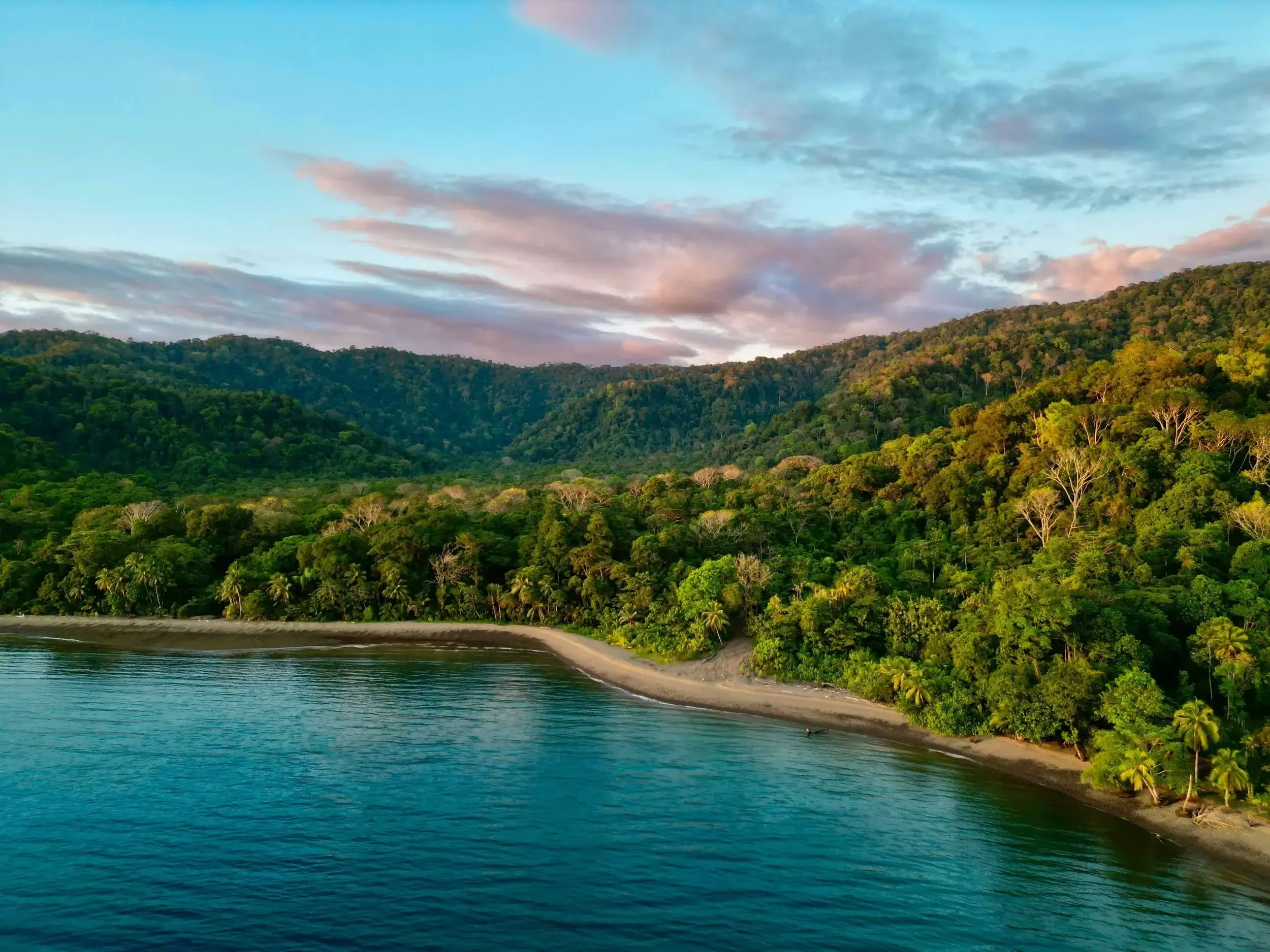 View of the Golfo Dulce at sunset from the Pavones shoreline, warm golden light on calm water