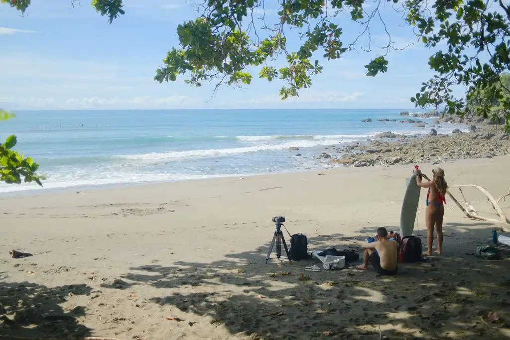 Surf coach reviewing video footage with an intermediate surfer on the beach at Pavones