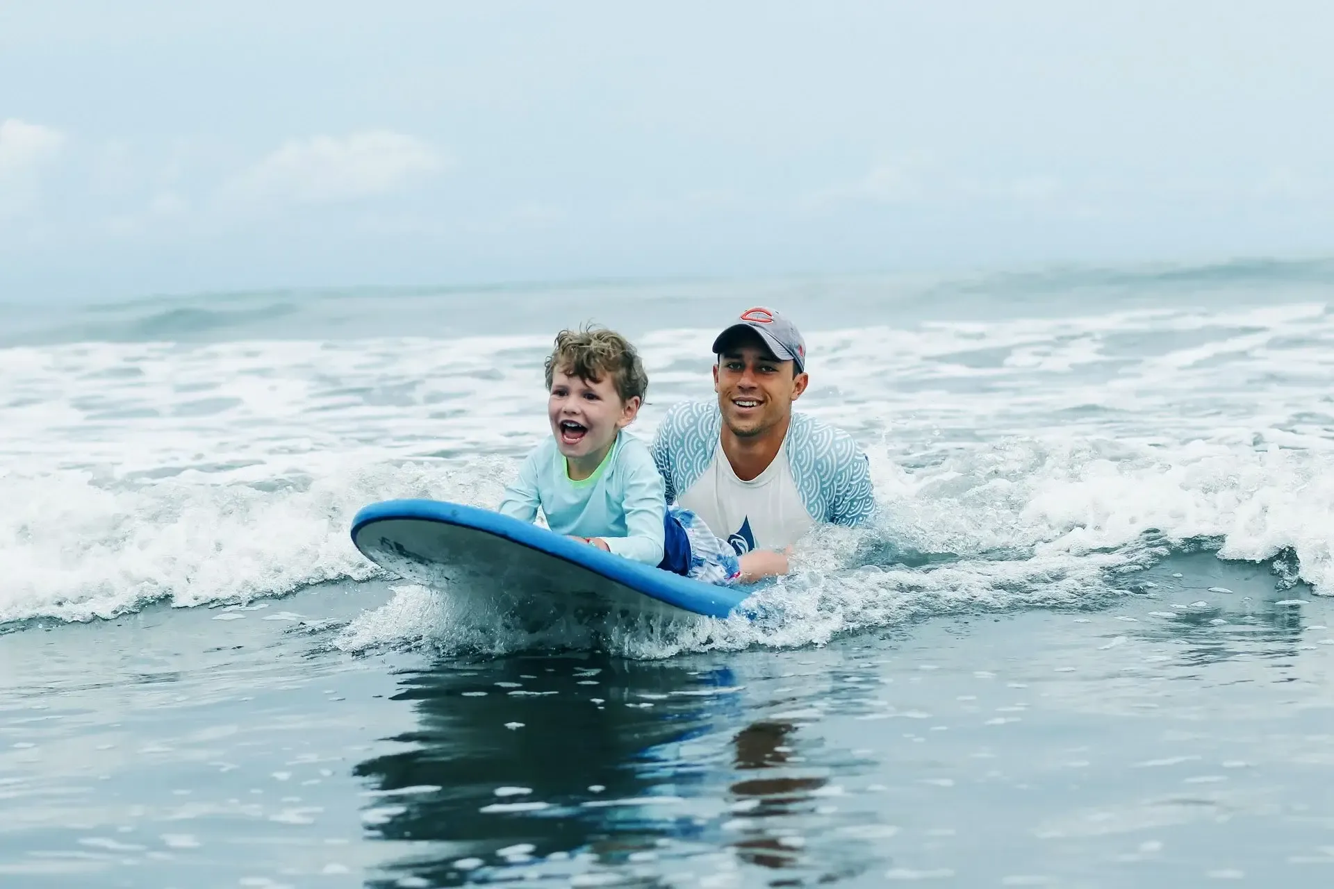 Coach helping a child catch a small whitewater wave at a Pavones surf camp