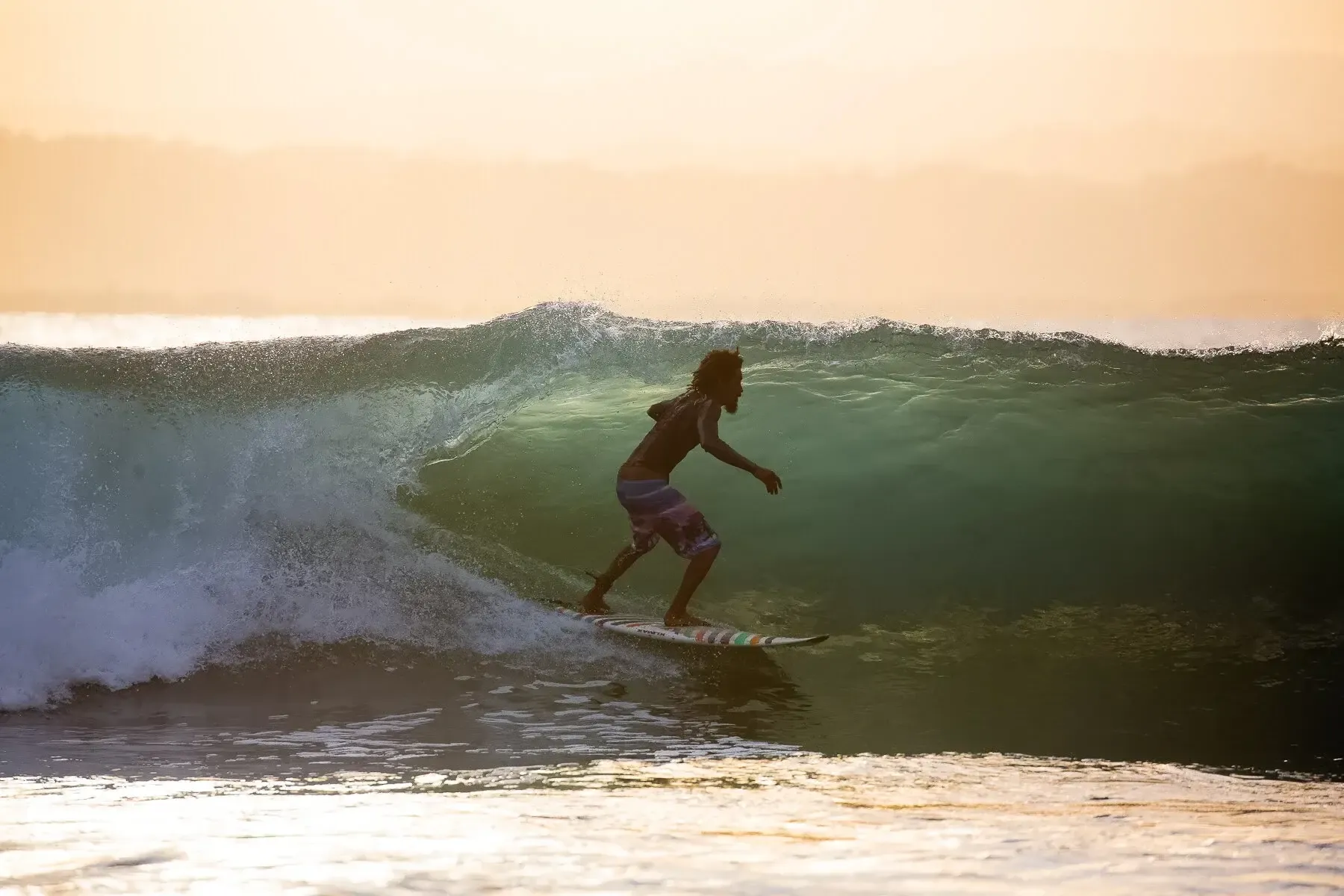 Evening light over the water at Pavones as a surfer paddles out