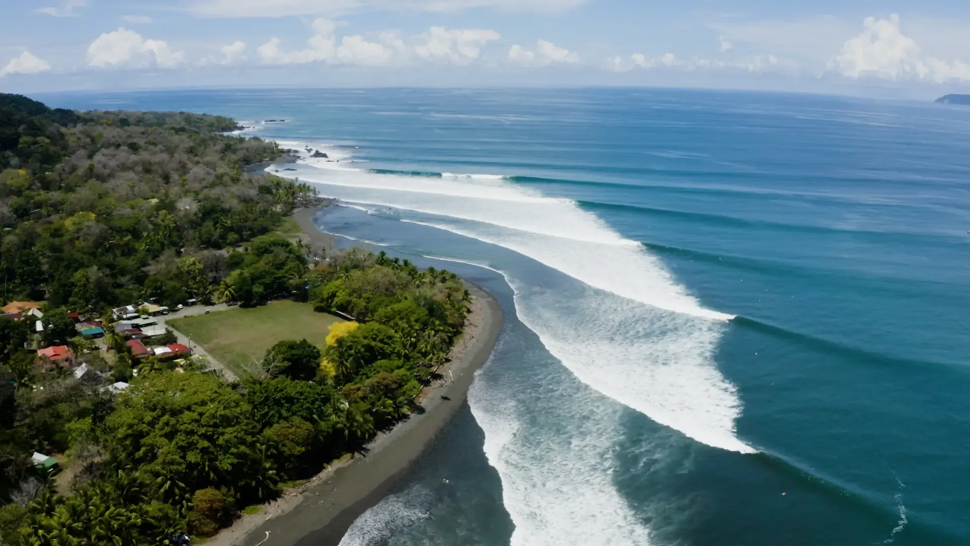 Long left-hand point break wave peeling at Pavones with a surfer riding the wall