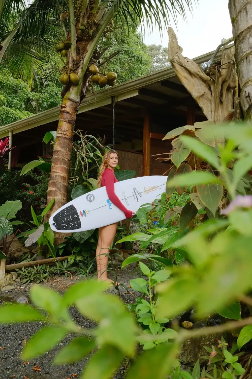 Female surfer walking back to Pavones Surf Camp after a session, surfboard under arm