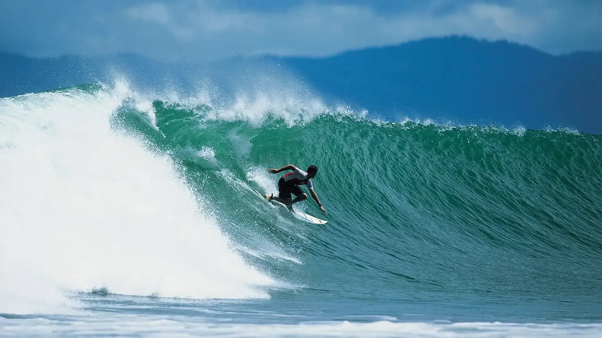 Surfer riding a long left at the Pavones point on a surf trip in Costa Rica